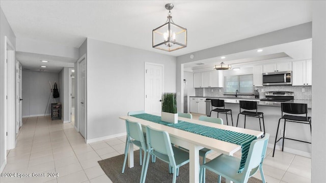 dining room with light tile patterned flooring, sink, and an inviting chandelier