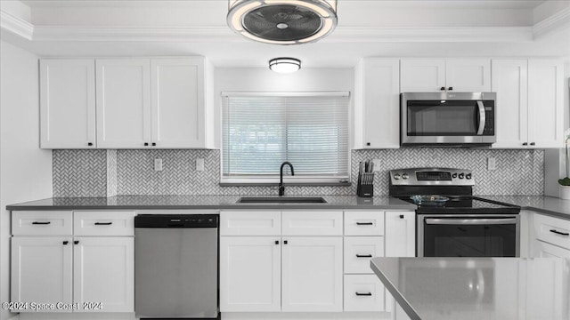 kitchen with stainless steel appliances, dark countertops, white cabinets, and a sink