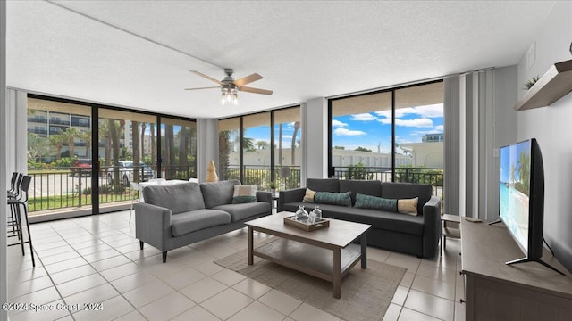 tiled living room featuring ceiling fan, expansive windows, a textured ceiling, and plenty of natural light