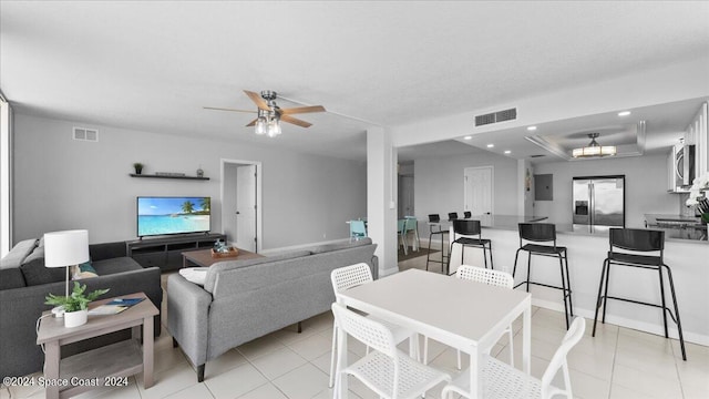 tiled living room with ceiling fan and a raised ceiling