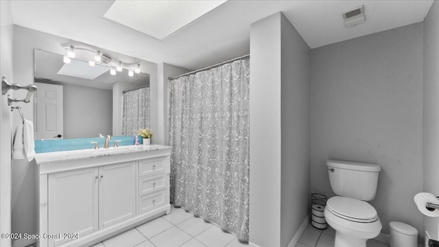 bathroom with tile patterned floors, a skylight, vanity, and toilet