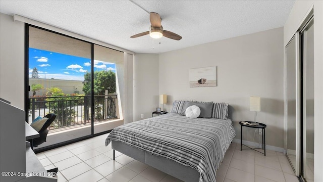 tiled bedroom with a textured ceiling, a ceiling fan, baseboards, access to exterior, and expansive windows