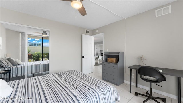 tiled bedroom with ceiling fan and a textured ceiling