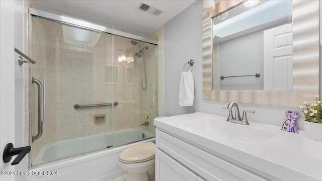 full bathroom with tile patterned floors, vanity, bath / shower combo with glass door, and toilet