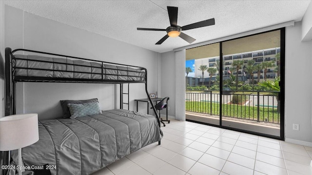 bedroom with baseboards, tile patterned floors, access to outside, a wall of windows, and a textured ceiling