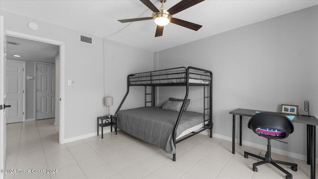 bedroom with ceiling fan, light tile patterned floors, and a textured ceiling