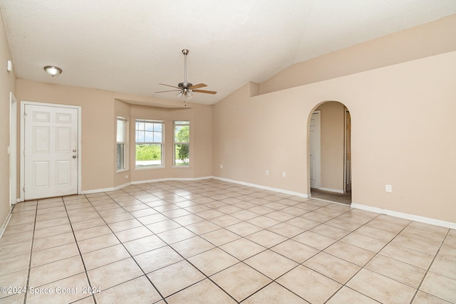 tiled empty room with ceiling fan and vaulted ceiling