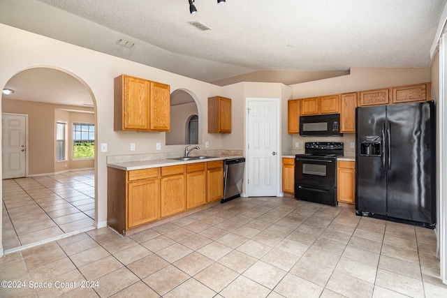 kitchen featuring a textured ceiling, black appliances, light tile patterned flooring, vaulted ceiling, and sink