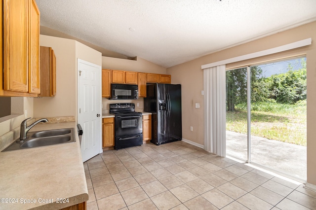 kitchen with vaulted ceiling, sink, light tile patterned flooring, refrigerator, and range