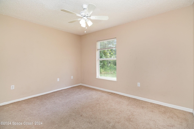 carpeted empty room featuring ceiling fan and a textured ceiling