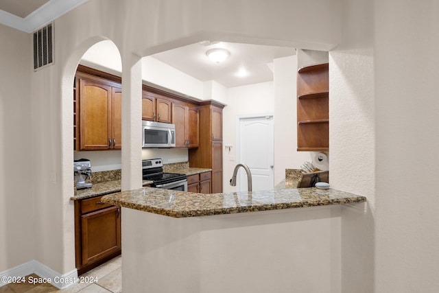 kitchen with stainless steel appliances, dark stone countertops, light tile patterned floors, sink, and kitchen peninsula