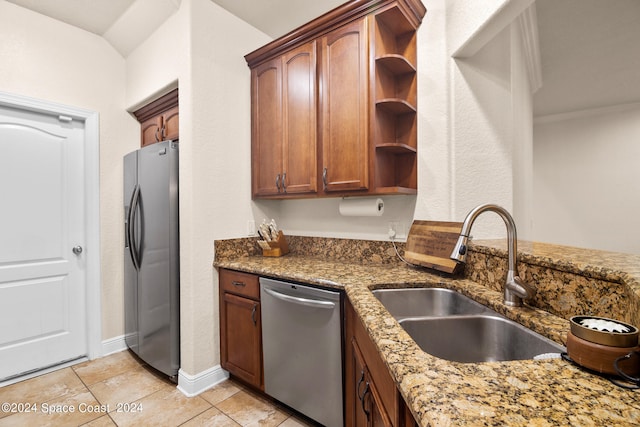 kitchen with appliances with stainless steel finishes, sink, dark stone countertops, and light tile patterned floors