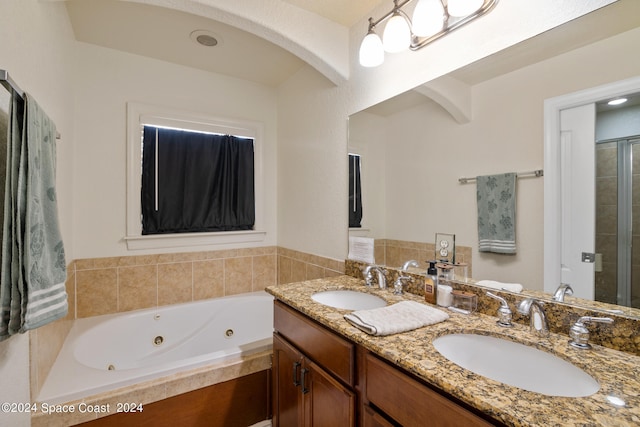 bathroom with dual vanity and a relaxing tiled tub