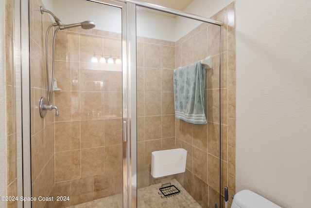 bathroom with a shower with door and toilet