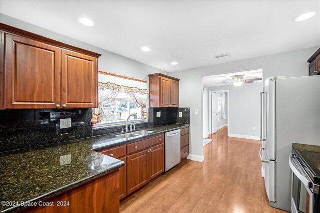 kitchen featuring light hardwood / wood-style flooring, tasteful backsplash, dishwashing machine, ceiling fan, and dark stone countertops