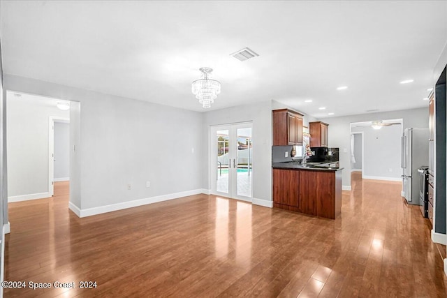 kitchen featuring hardwood / wood-style floors, french doors, sink, kitchen peninsula, and a notable chandelier