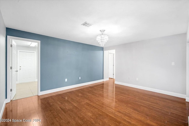 spare room featuring a notable chandelier and hardwood / wood-style flooring