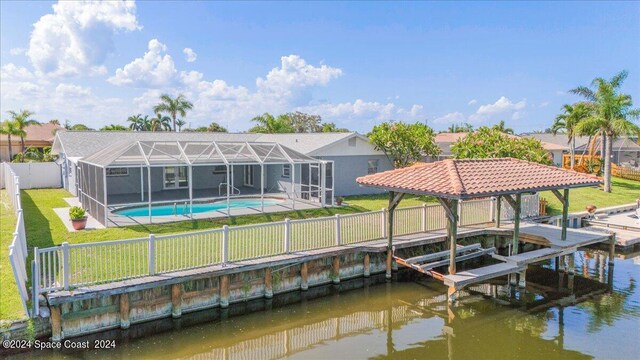 view of dock with glass enclosure, a lawn, a water view, and a fenced in pool