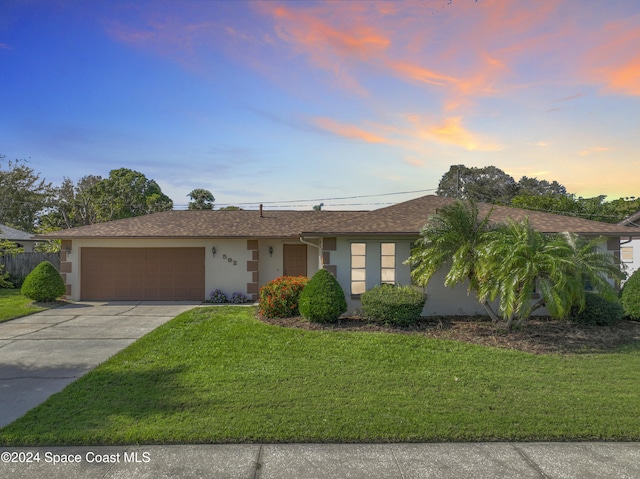 ranch-style home with a garage and a lawn