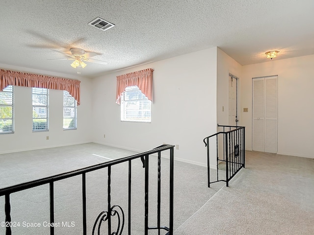 carpeted spare room with a textured ceiling and ceiling fan