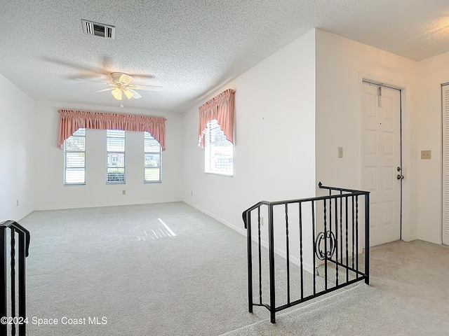 carpeted empty room with ceiling fan and a textured ceiling