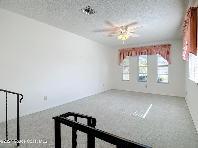 unfurnished room with ceiling fan, light colored carpet, and a textured ceiling