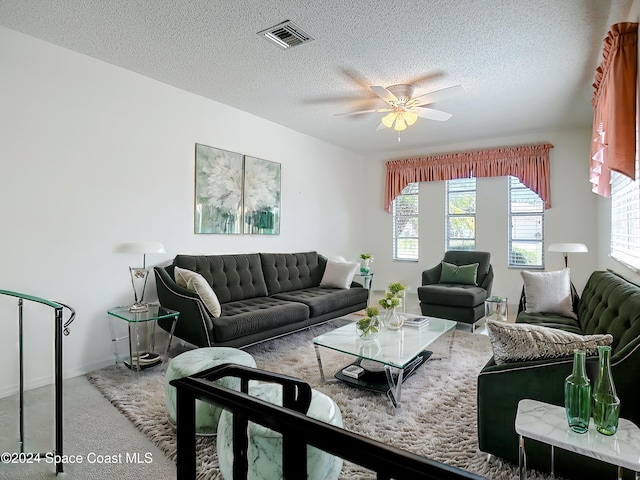 carpeted living room featuring ceiling fan and a textured ceiling