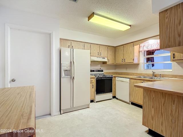 kitchen featuring tasteful backsplash, sink, a textured ceiling, and white appliances