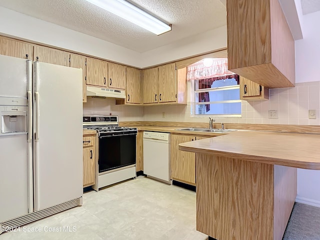 kitchen with sink, white appliances, kitchen peninsula, and backsplash