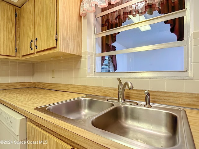 kitchen with white dishwasher, sink, and tasteful backsplash