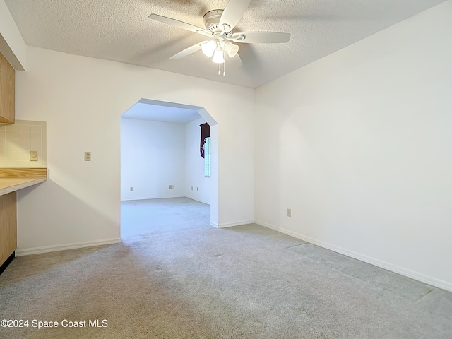 carpeted spare room featuring a textured ceiling and ceiling fan