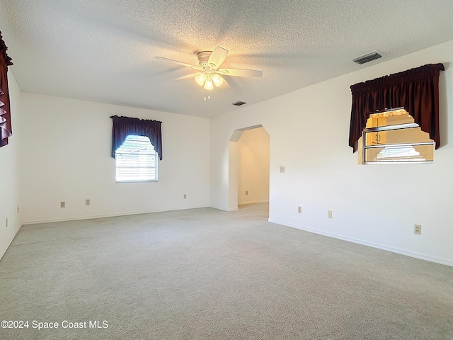 empty room featuring ceiling fan, light carpet, and a textured ceiling