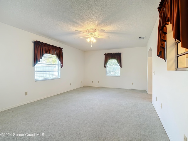 spare room with ceiling fan, light colored carpet, and a textured ceiling