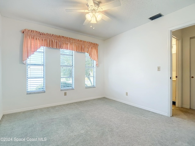 empty room with ceiling fan, a textured ceiling, and carpet