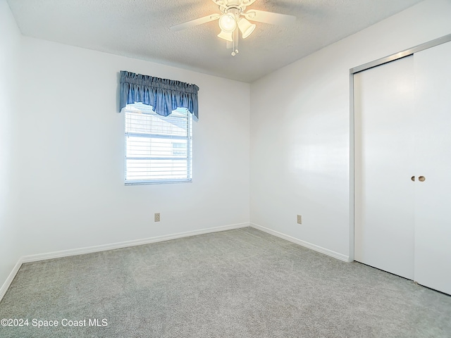 unfurnished bedroom with ceiling fan, a closet, carpet floors, and a textured ceiling