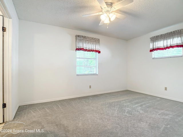 empty room featuring ceiling fan, light carpet, and a textured ceiling