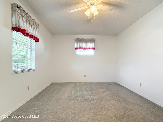 unfurnished room with plenty of natural light, carpet floors, a textured ceiling, and ceiling fan