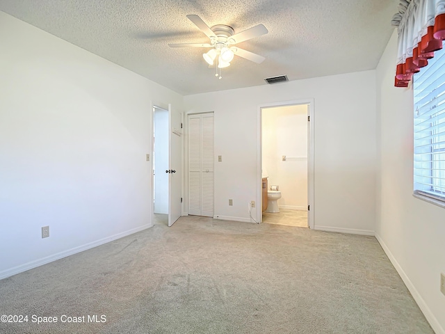 unfurnished bedroom with light carpet, connected bathroom, a textured ceiling, and ceiling fan