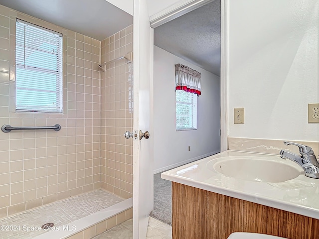 bathroom featuring tile patterned floors, vanity, and a tile shower