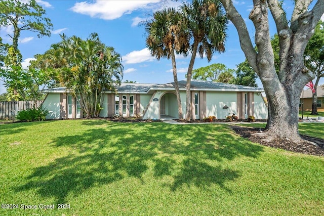 ranch-style home with a front yard, fence, and stucco siding