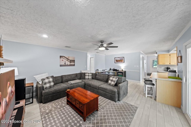 living area featuring a textured ceiling, ceiling fan, wood finish floors, baseboards, and ornamental molding