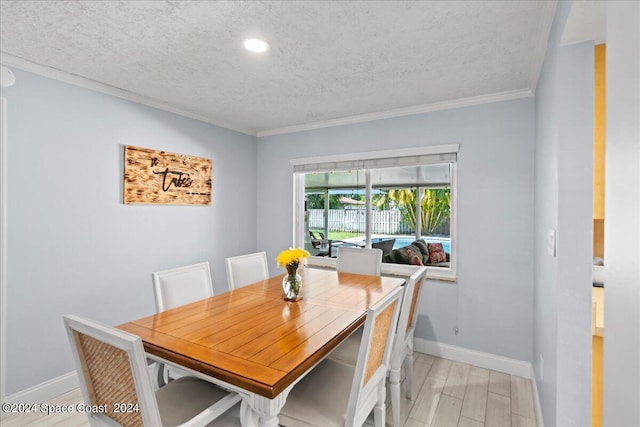 dining room with light wood-style flooring, ornamental molding, a textured ceiling, and baseboards