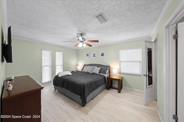 bedroom with light wood-type flooring, ceiling fan, multiple windows, and visible vents