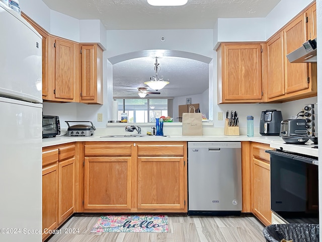 kitchen with white refrigerator, dishwasher, sink, and a textured ceiling