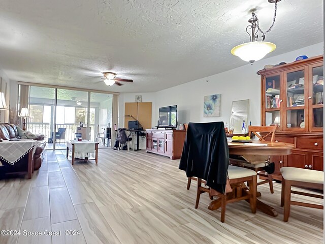 dining room featuring ceiling fan, floor to ceiling windows, a textured ceiling, and light wood-type flooring