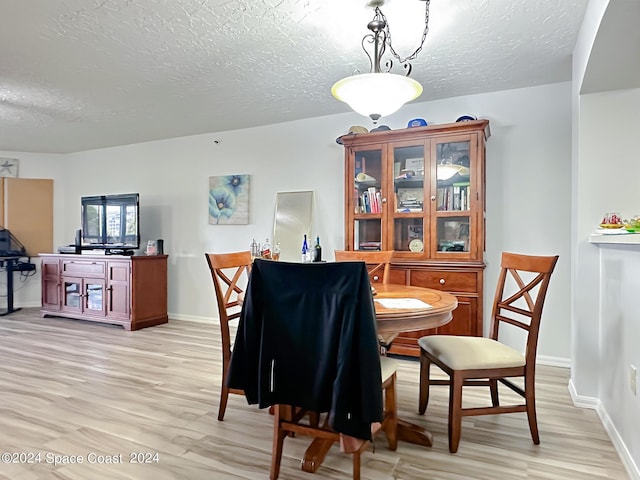 dining area featuring light hardwood / wood-style floors and a textured ceiling