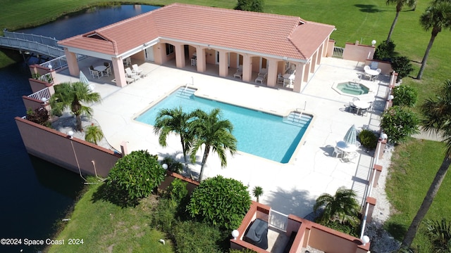 view of swimming pool with a patio area, a hot tub, and a water view