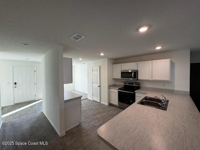 kitchen featuring visible vents, stainless steel appliances, white cabinetry, a sink, and recessed lighting