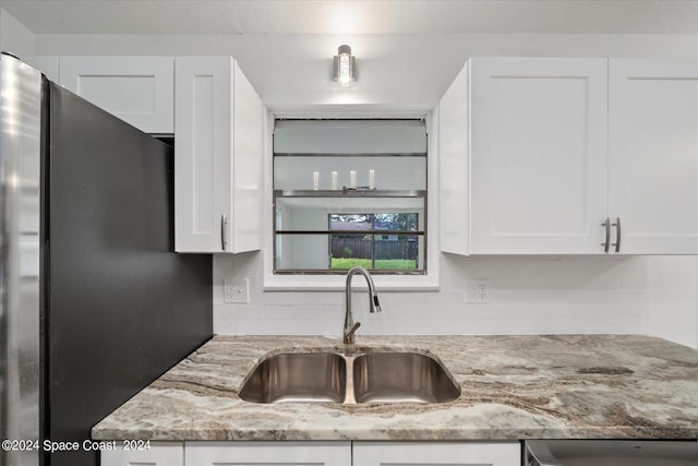 kitchen with white cabinetry, sink, and stainless steel fridge