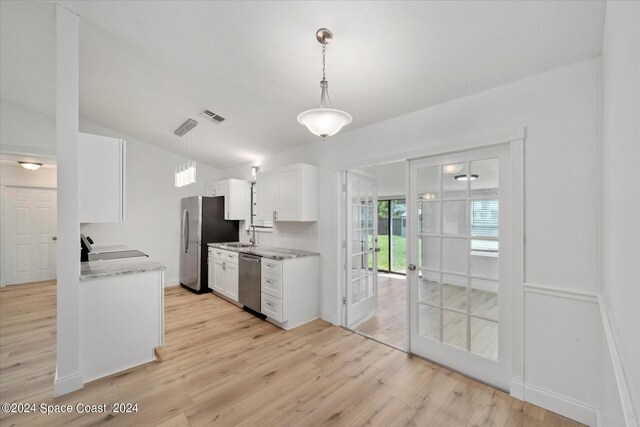 kitchen featuring light hardwood / wood-style flooring, white cabinetry, hanging light fixtures, and stainless steel appliances